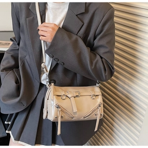 Detail of light apricot glossy leather crossbody bag with metal zippers and buckle