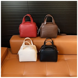 Showcase of four faux leather handbags in red, coffee, cream, and black on a sofa
