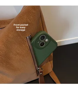 Détail du sac en cuir marron avec poche zippée avant et un smartphone vert à l'intérieur