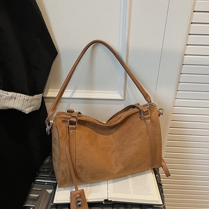 Dettaglio di una borsa a cilindro in camoscio marrone con lucchetto in metallo argento