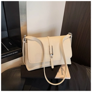 Detailed view of cream white leather shoulder bag with lychee texture and silver buckle