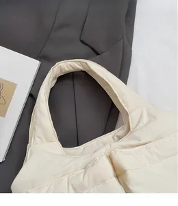 Close-up of cream quilted bucket bag with padded handle and minimalist nylon texture