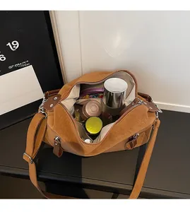Vue détaillée de l'intérieur spacieux du sac hobo en daim marron avec des cosmétiques