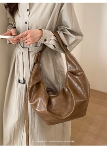 Détail du sac croissant marron foncé montrant la texture plissée et le style rétro épuré