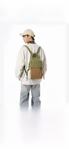 Side view of an olive green and brown patchwork backpack worn by a model in a studio