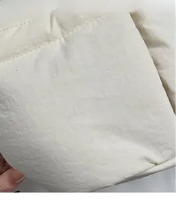 Macro shot of quilted creamy white fabric texture on a large capacity bucket bag