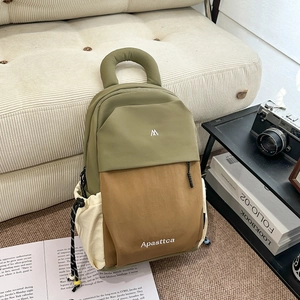 Detail of color-block nylon backpack featuring drawstring pockets and side logo