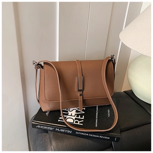Detail of a brown lychee pattern leather shoulder bag with a metal vertical buckle closure