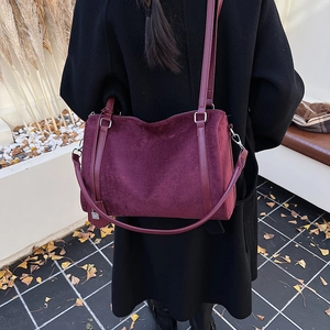 Dettaglio della borsa tote in pelle scamosciata bordeaux indossata con cappotto nero
