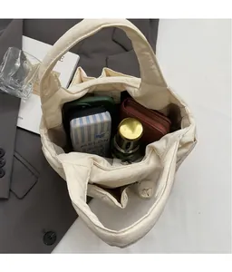 Macro view showing the spacious interior storage of the cream nylon bucket tote bag