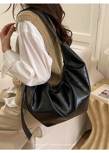 Gros plan d'un sac à bandoulière minimaliste noir en cuir brillant de forme demi-lune