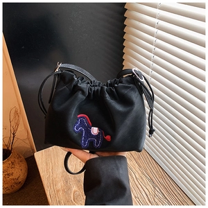 Detail of black drawstring bucket bag with blue and red pony embroidery in soft lighting
