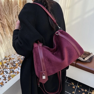 Dettaglio borsa tote in velluto bordeaux con manici in pelle e lucchetto argentato decorativo