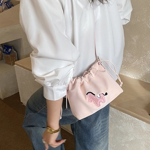 Detail view of pink drawstring bucket bag with cloud embroidery on a casual model