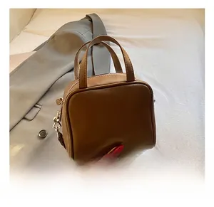 Close-up of caramel brown handbag with dual handles and gold-toned metal hardware details
