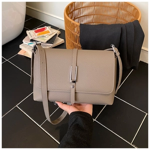 Detail of taupe litchi grain leather shoulder bag with silver buckle and vertical strap