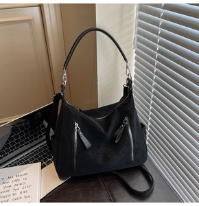 Détail du sac hobo noir mat avec poche zippée argentée et bretelles réglables