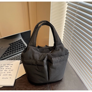Detail of black quilted nylon bucket bag with multiple functional exterior pockets for commuting