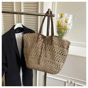 Macro view of woven straw tote bag with brown leather handles and a bouquet of yellow flowers