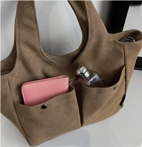Detailed view of brown canvas tote with dual front pockets and striped inner lining
