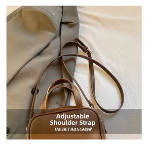 Detail of brown faux leather handbag showing the adjustable thin shoulder strap