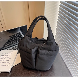 Detail view of black quilted bucket bag featuring two spacious front pockets and soft padding
