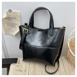 Dettaglio borsa tote in pelle nera lucida con cuciture fini e fibbia in metallo dorato