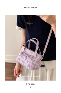 Detail showing lilac handbag with cat patterns, checkered texture, and bow ornament