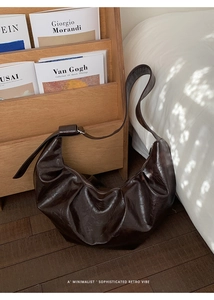 Détail d'un sac demi-lune marron foncé en cuir ciré plissé avec un design rétro chic
