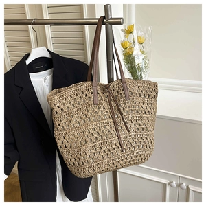 Detail view of woven straw tote bag featuring hollow texture and brown leather handles