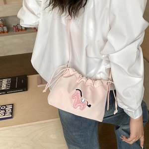 Detail of pink drawstring bucket bag with cute plush pony patch worn by model