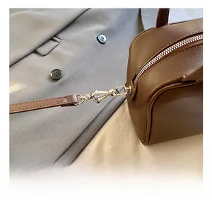 Detail view of dark brown leather handbag with silver metal lobster hook and zipper closure