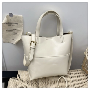 Borsa tote minimalista in pelle PU bianco crema con tracolla regolabile su sedia di vimini