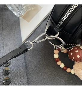 Detail of premium silver hardware on black leather bag with stylish beaded charms