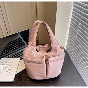 Detail of dusty pink padded tote bag featuring dual front pockets and quilted nylon texture