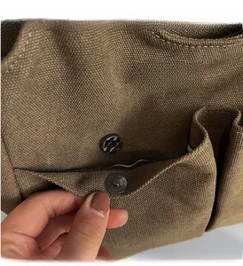 Close-up of magnetic snap closure and textured fabric on khaki canvas handbag