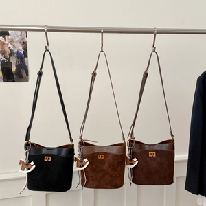 Close-up of three suede bucket bags in black, light brown and coffee with horse charm