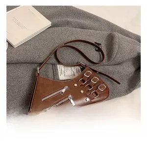 Detailed macro view of a brown faux leather crescent bag with silver buckles and zippers