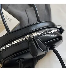 Close-up of smooth dual silver metal zippers on black matte leather bowling bag