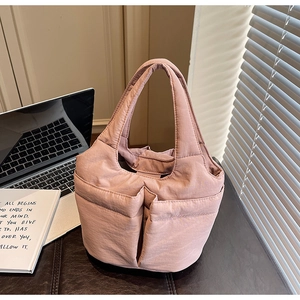 Close-up of pink quilted bucket bag showing functional front pockets and soft texture