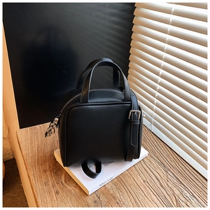 Detail view of black matte leather handbag with adjustable strap on a lifestyle background