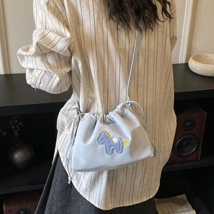 Detail of light blue drawstring bucket bag featuring a purple plush horse embroidery patch