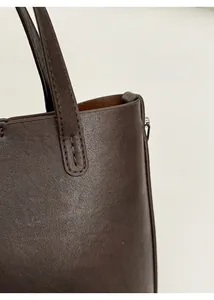Détail des coutures renforcées de la poignée et du passepoil en cuir du sac seau marron foncé
