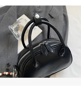 Detailed view of black bowling bag with cylindrical handles and silver metal hardware accents