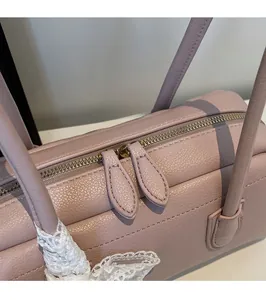 Close-up of golden hardware zipper and pink pebbled leather on a Boston handbag