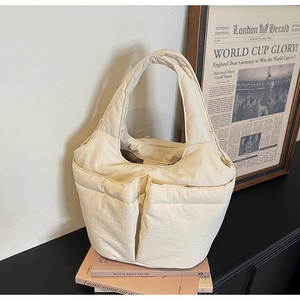 Close-up of cream utility bucket bag with dual front pockets and wide top handle