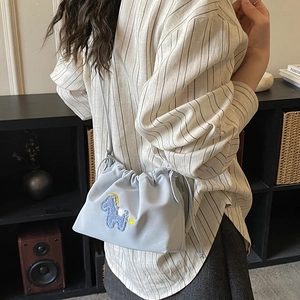 Detail of light blue drawstring bucket bag featuring a colorful pony embroidery