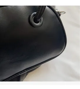 Detailed macro view of black leather texture and metal ring fasteners on the shoulder bag