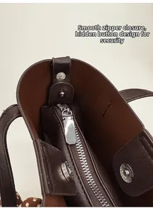 Détail du sac cabas en cuir marron foncé avec fermeture éclair argentée et fermoir magnétique