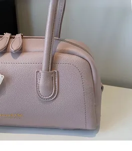 Detail showing the lychee grain leather texture and gold embossed logo on pink Boston bag